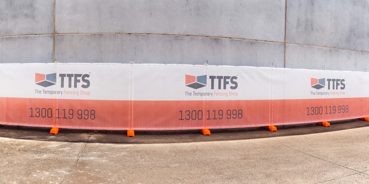 A temporary fence with printed shade cloth installed for advertising.
