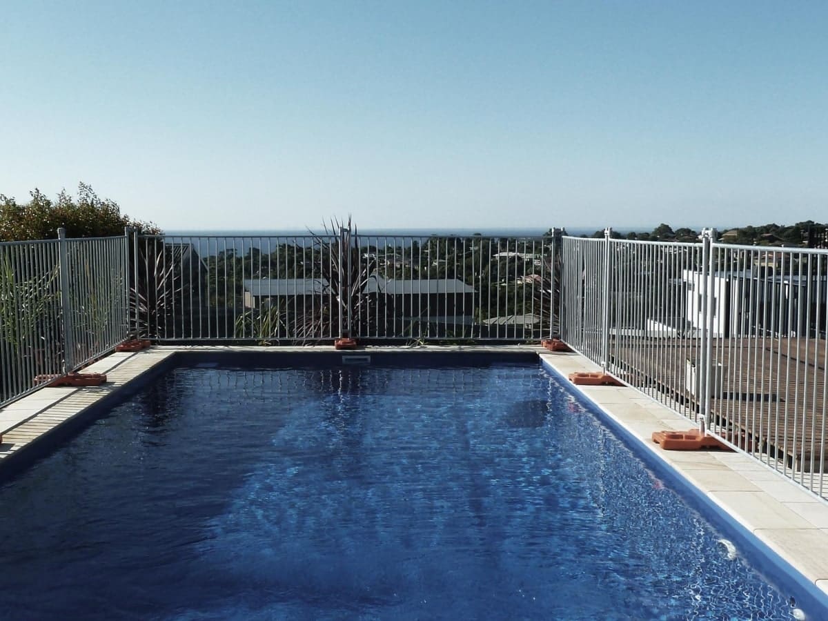 A pool are surrounded by a sturdy, temporary pool fencing system, illustrating a temporary yet secure measure under Australian pool fence regulations.