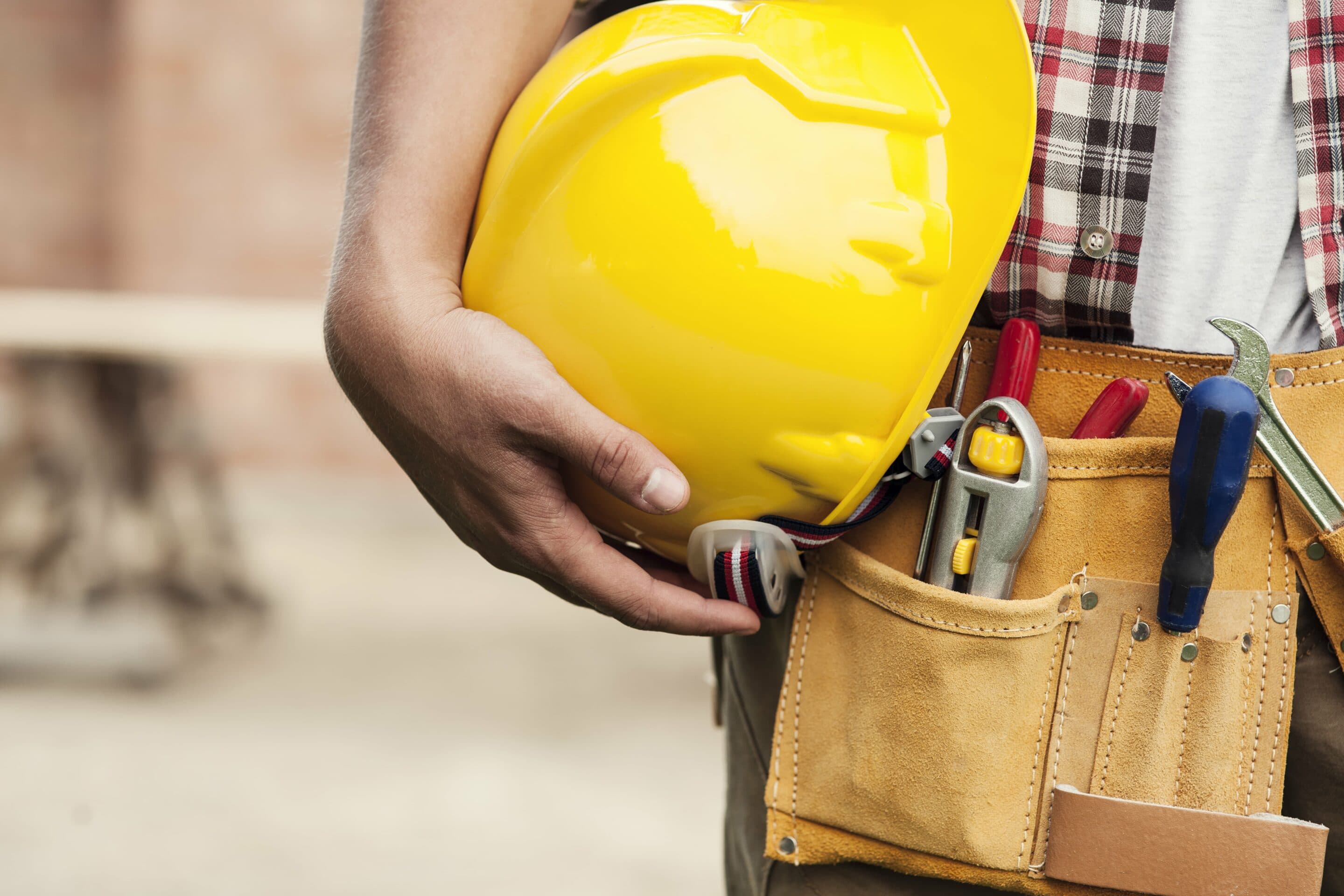 Close up of a workers tool belt and hard hat.