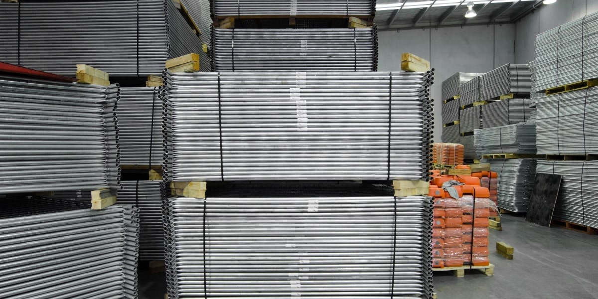 Stacks of galvanised steel temporary fencing products in a warehouse.