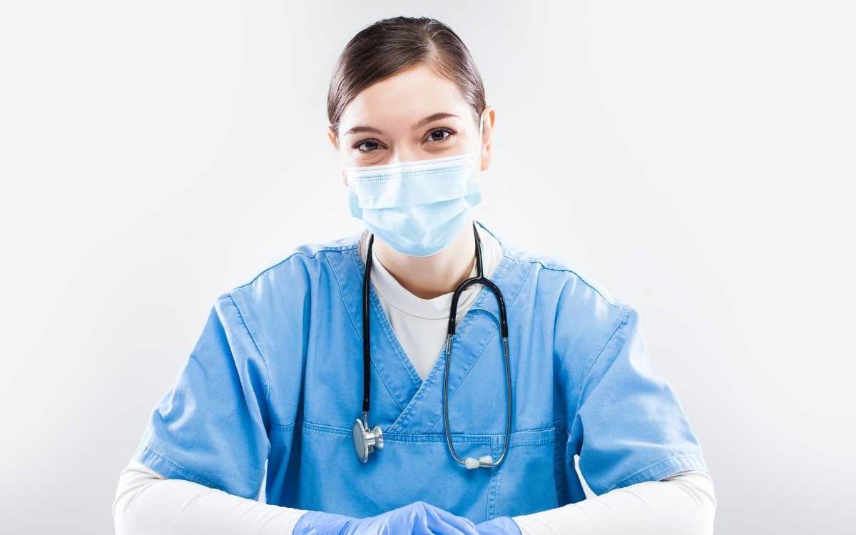 Lady wearing different types of PPE gear, including face mask, gloves and apron.