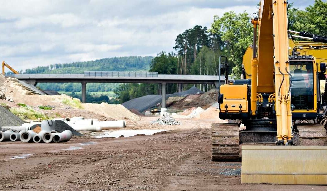 Construction site with yellow goods and pipe in the background.