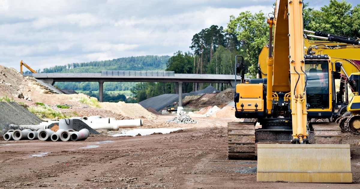 Construction site with yellow goods and pipe in the background.