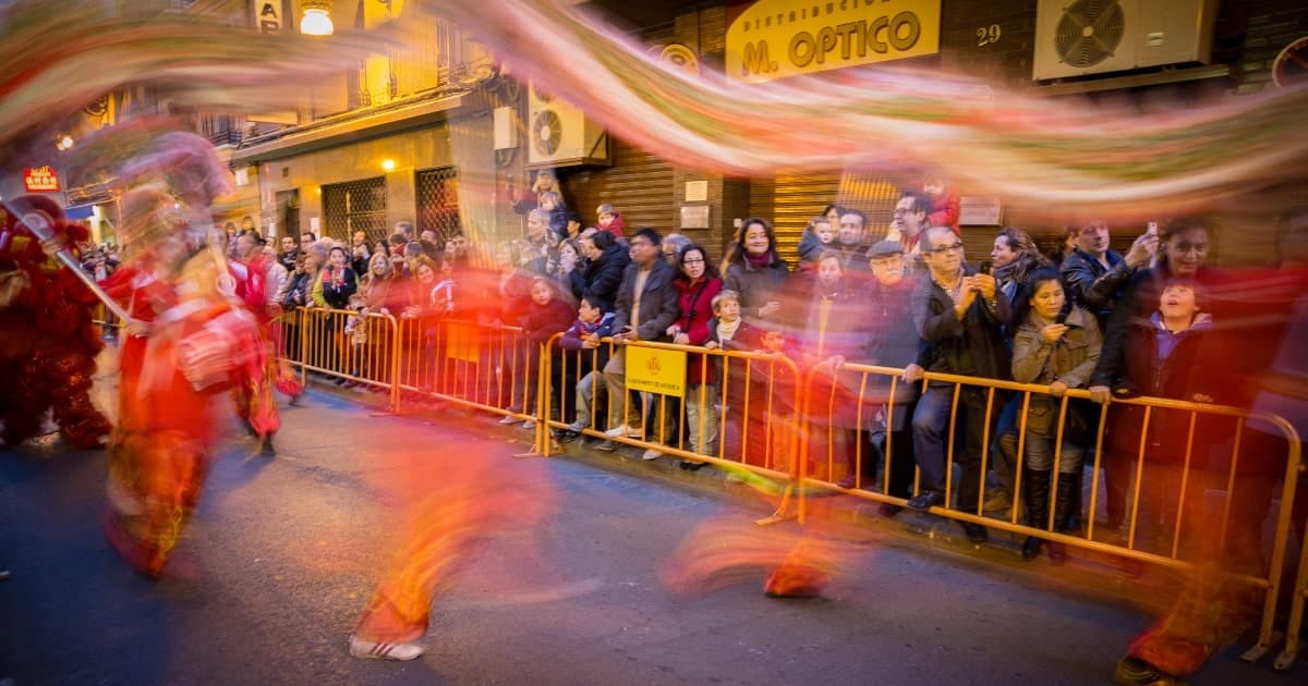 Crowd behind yellow pedestrian fencing watching Chinese New Year parade.