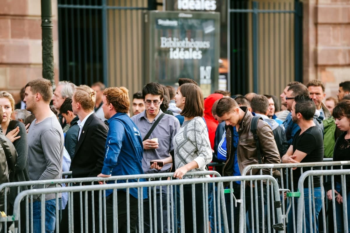 People lining up outside a store behind crowd control barriers.