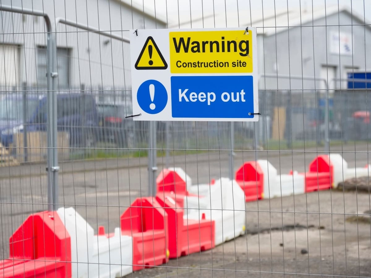 Construction site warning and keep ou sign on fenced area.