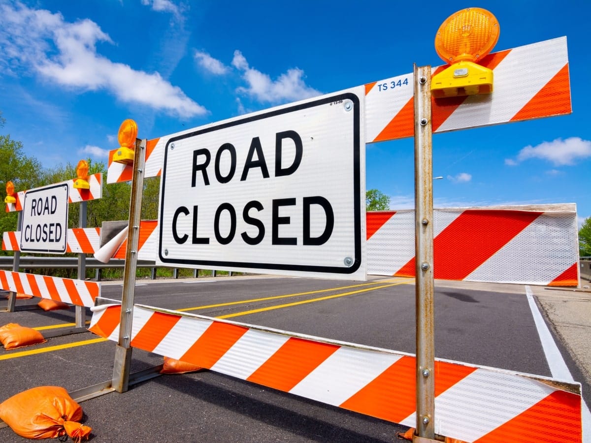 Road closed corflute sign and barrier to redirect traffic.