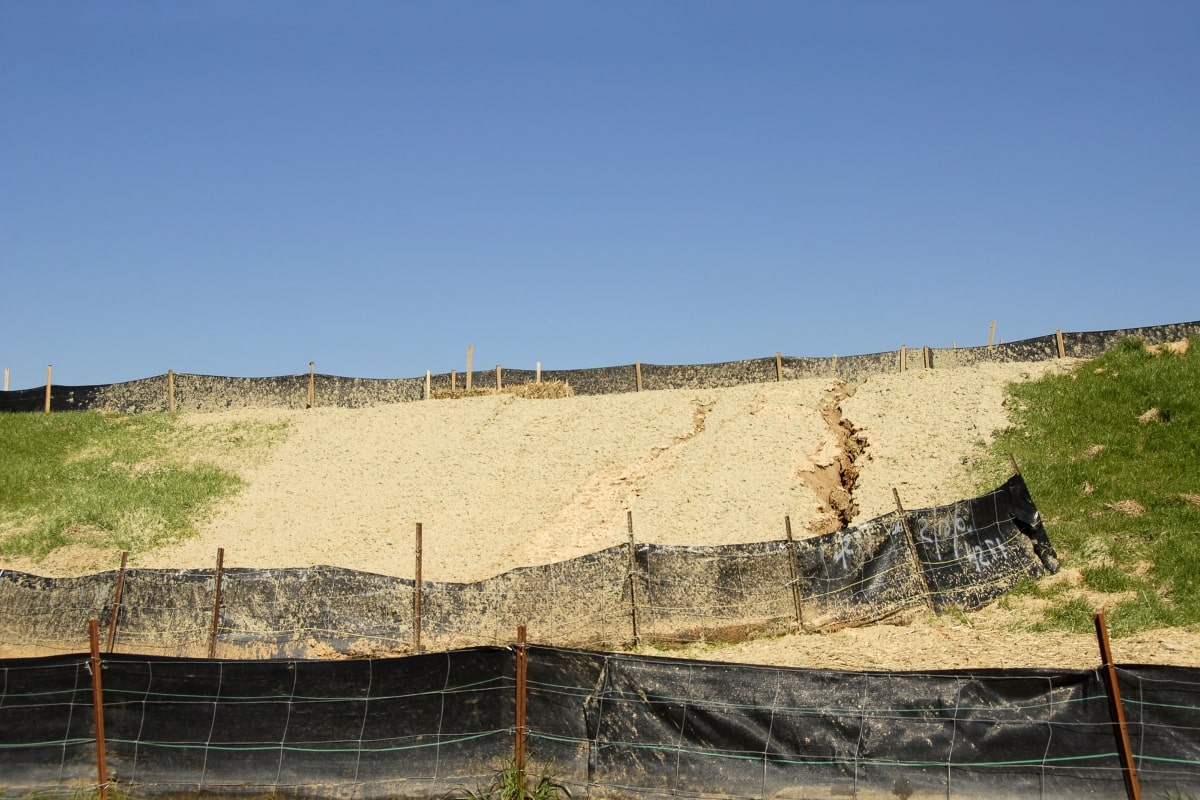 Sediment fencing set up on sandy hillside to help prevent soil erosion.