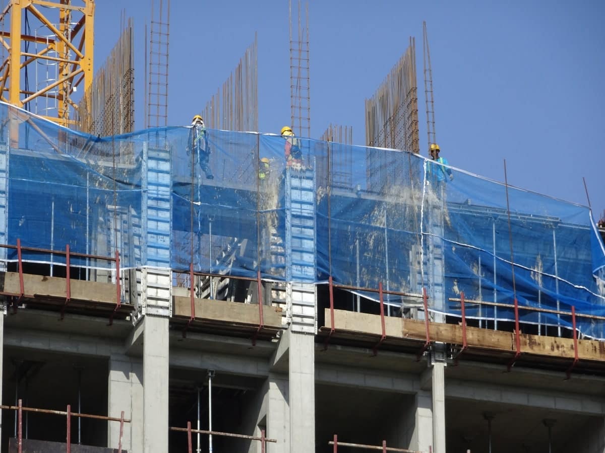 Large construction project, with blue scaffold net on outside of building.