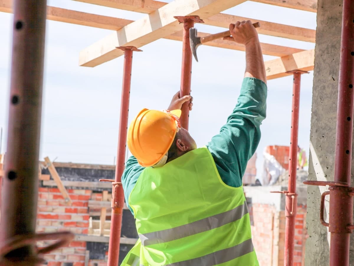 A construction worker using tools on a construction site, highlighting the potential risk of falling objects and debris which can cause serious injuries or even fatalities.