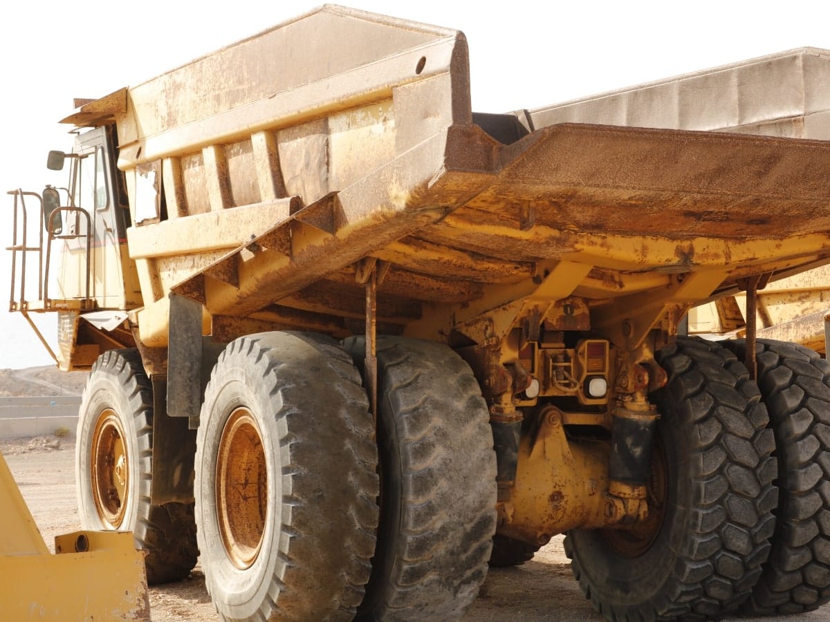 A large vehicle moving through a construction site, posing a potential risk of  collisions and worker injuries.