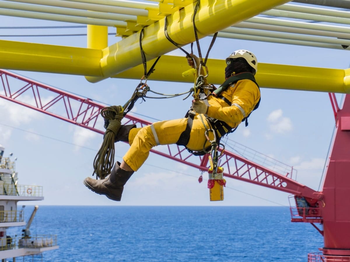 Image depicting a worker wearing a harness, working at heights on a construction site.