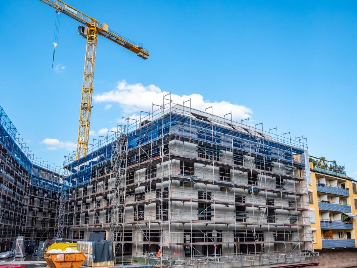 An image depicting the essential safety measures of edge protection on a multi-storey building under construction, with a towering crane in the backdrop.