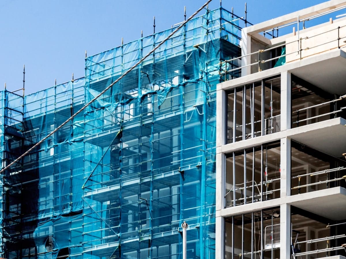 Blue scaffolding netting wrapped around scaffolding on a multi-storey structure illustrates a proactive approach to mitigating the risk of falls and debris falling.