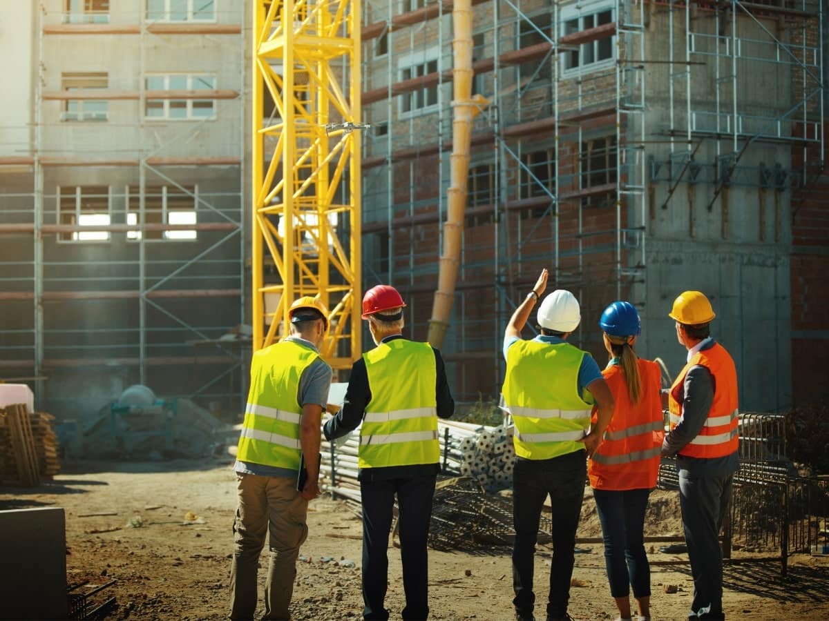 Five construction workers standing and observing the site.