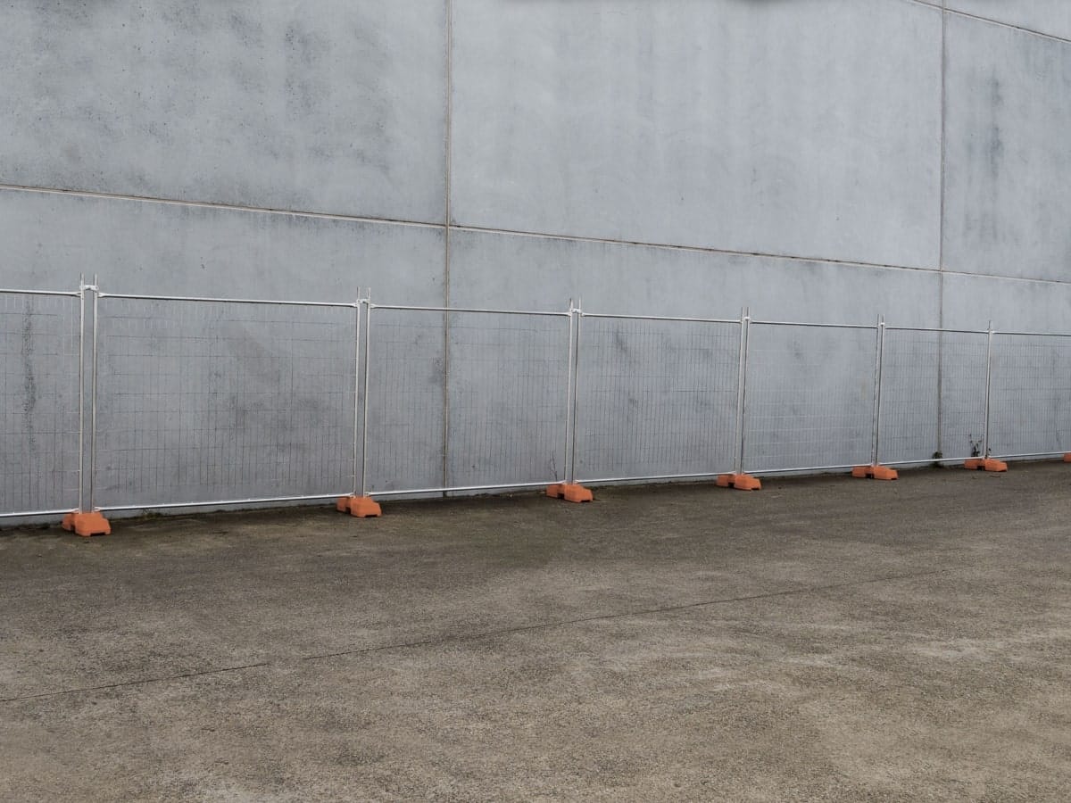 Effective fencing enclosing a construction area with a grey wall backdrop, demonstrating the essential steps to work safely at heights and secure the site.