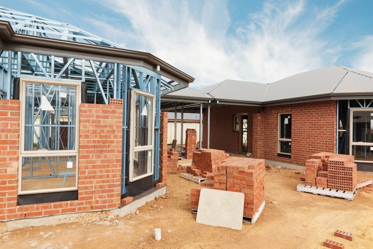 Construction site showing a home clost to the lockup stage, with stacks of bricks ready to complete the walls and secure the building structure.