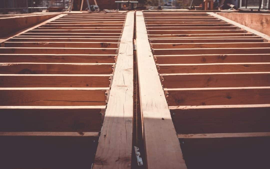 View of the initial framing stage of house construction, showcasing the skeletal structure and floor joists as the foundation of the home takes shape.