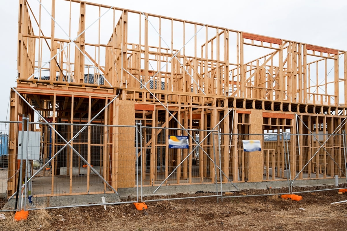 A house under construction, surrounded by temporary fencing to ensure privacy and security on the building site.