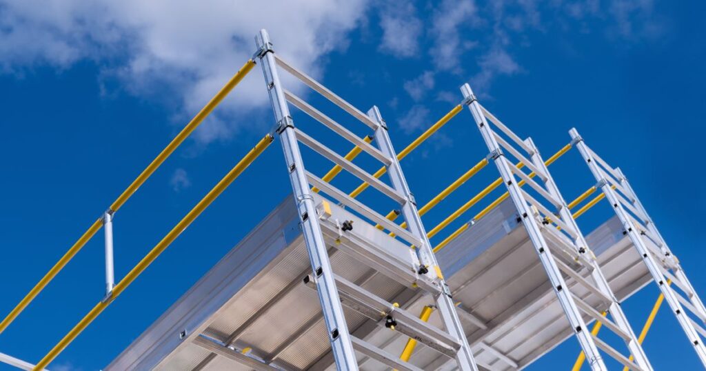 Top 10 Scaffolding Parts All Builders Should Know for Safe Construction 5 Blue sky behind scaffolding with ladder access.